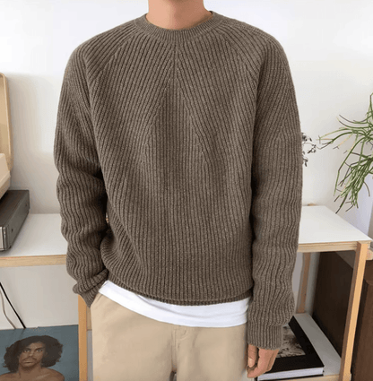 Men's brown relaxed-fit ribbed sweater featuring raglan sleeves and a 100% cotton knit construction.