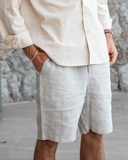 Men's beige linen shorts featuring an adjustable drawstring waistband and a refined tailored mid-thigh length.
