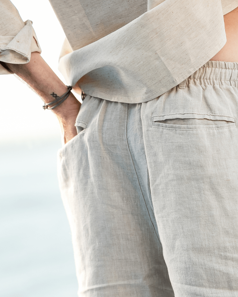 Men's beige linen shorts featuring an adjustable drawstring waistband and a refined tailored mid-thigh length.