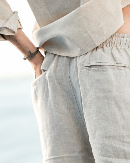 Men's beige linen shorts featuring an adjustable drawstring waistband and a refined tailored mid-thigh length.