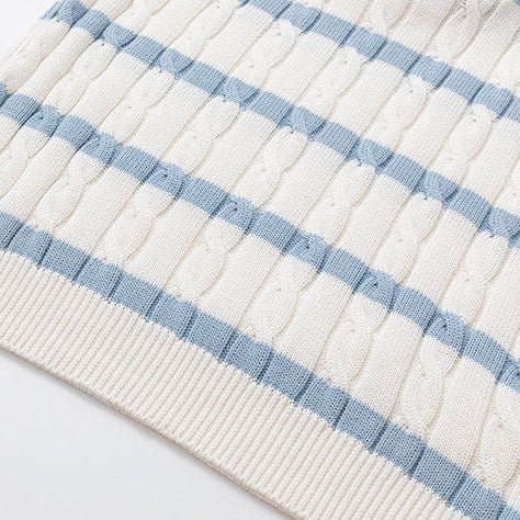 Close-up of a cream-colored silk and linen cable knit polo shirt with light blue horizontal stripes and a V-neck open collar, featuring clear frame sunglasses tucked into the neckline.