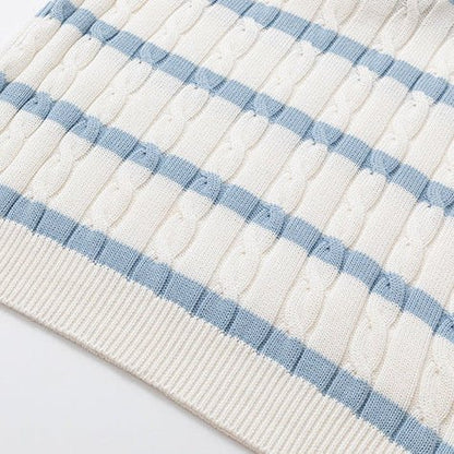 Close-up of a cream-colored silk and linen cable knit polo shirt with light blue horizontal stripes and a V-neck open collar, featuring clear frame sunglasses tucked into the neckline.