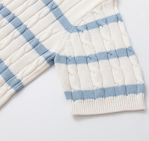 Close-up of a cream-colored silk and linen cable knit polo shirt with light blue horizontal stripes and a V-neck open collar, featuring clear frame sunglasses tucked into the neckline.