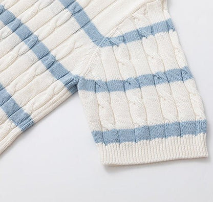 Close-up of a cream-colored silk and linen cable knit polo shirt with light blue horizontal stripes and a V-neck open collar, featuring clear frame sunglasses tucked into the neckline.
