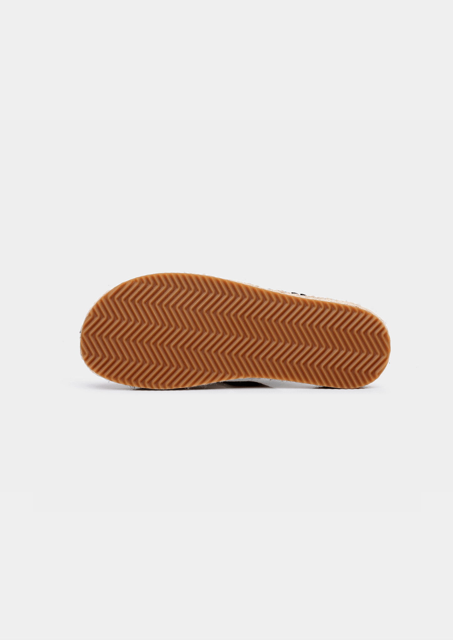 Close-up of a sandal sole with brown rubber tread on a white background