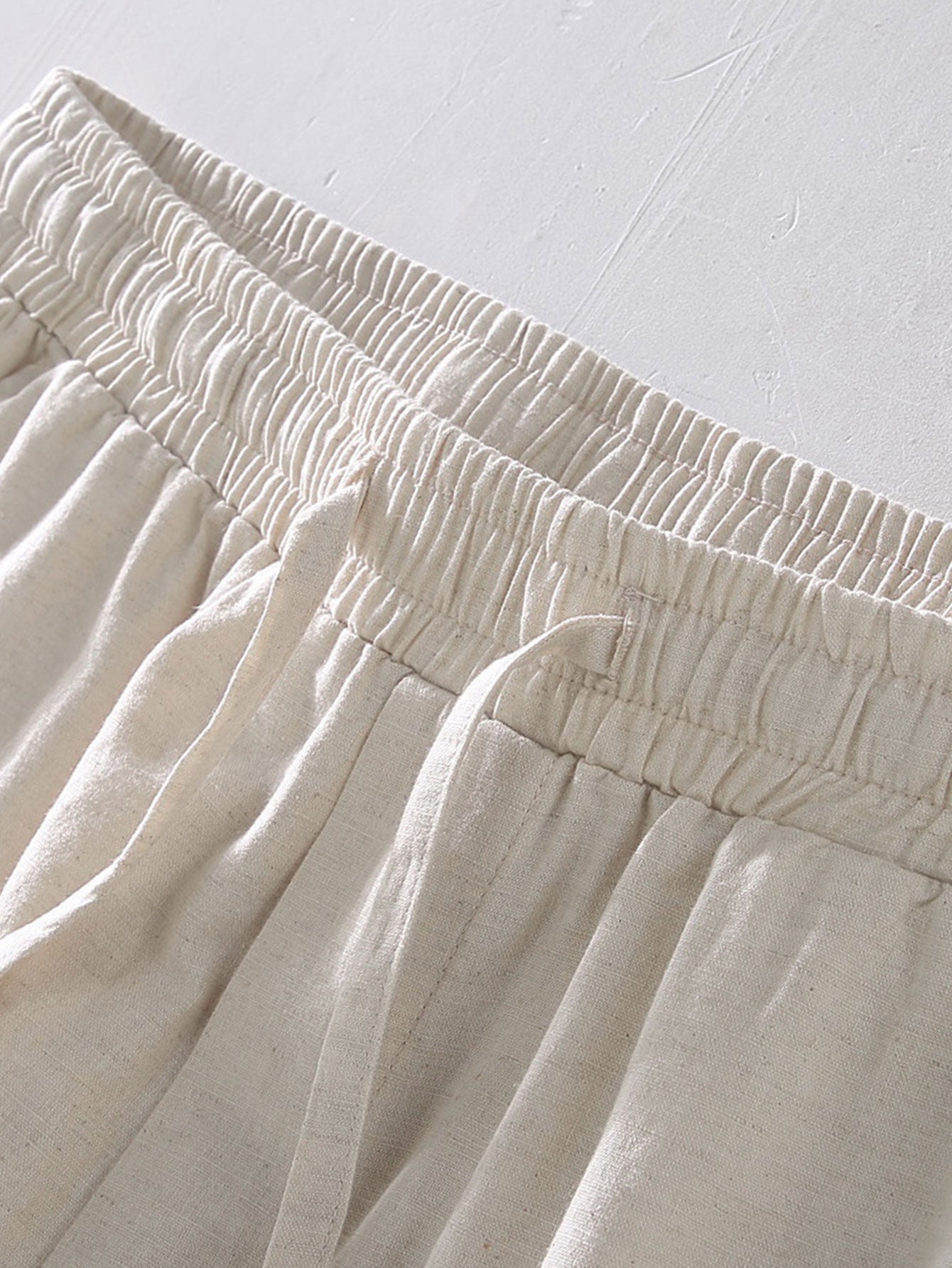 Close-up of beige pants with an elastic waistband on a light gray background