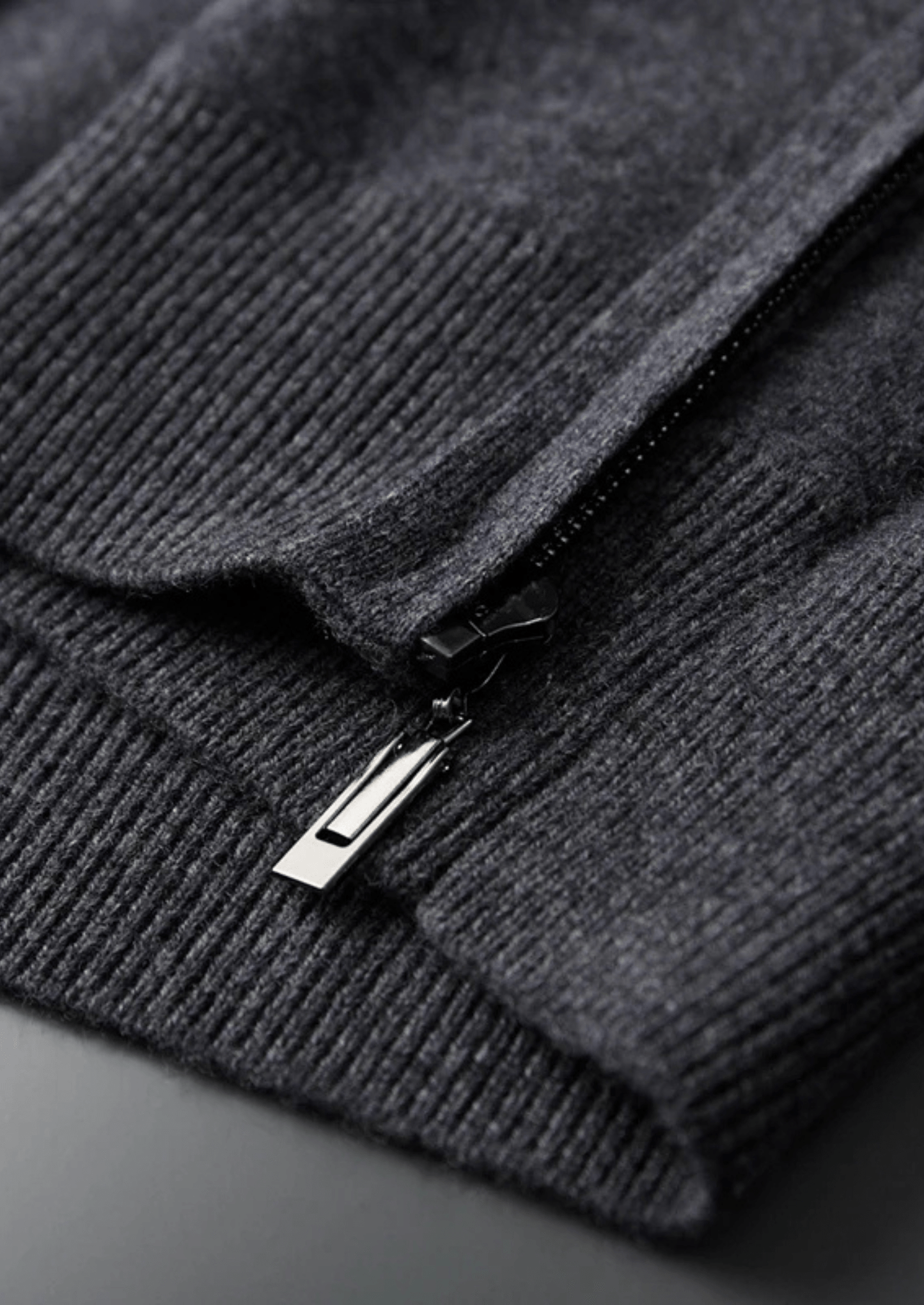 Close-up of a dark gray sweater with a zipper on a dark background