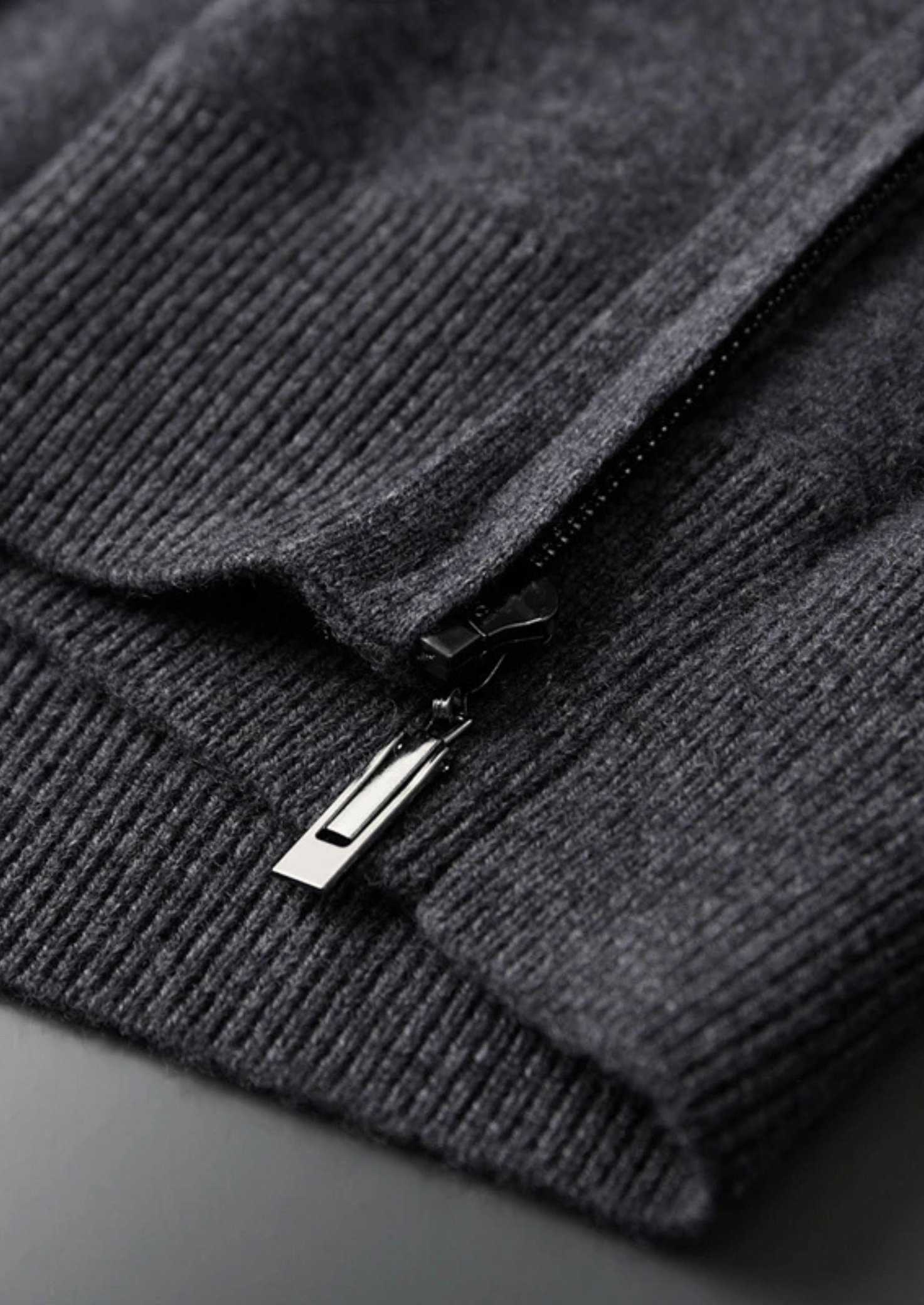 Close-up of a dark gray sweater with a zipper on a dark background