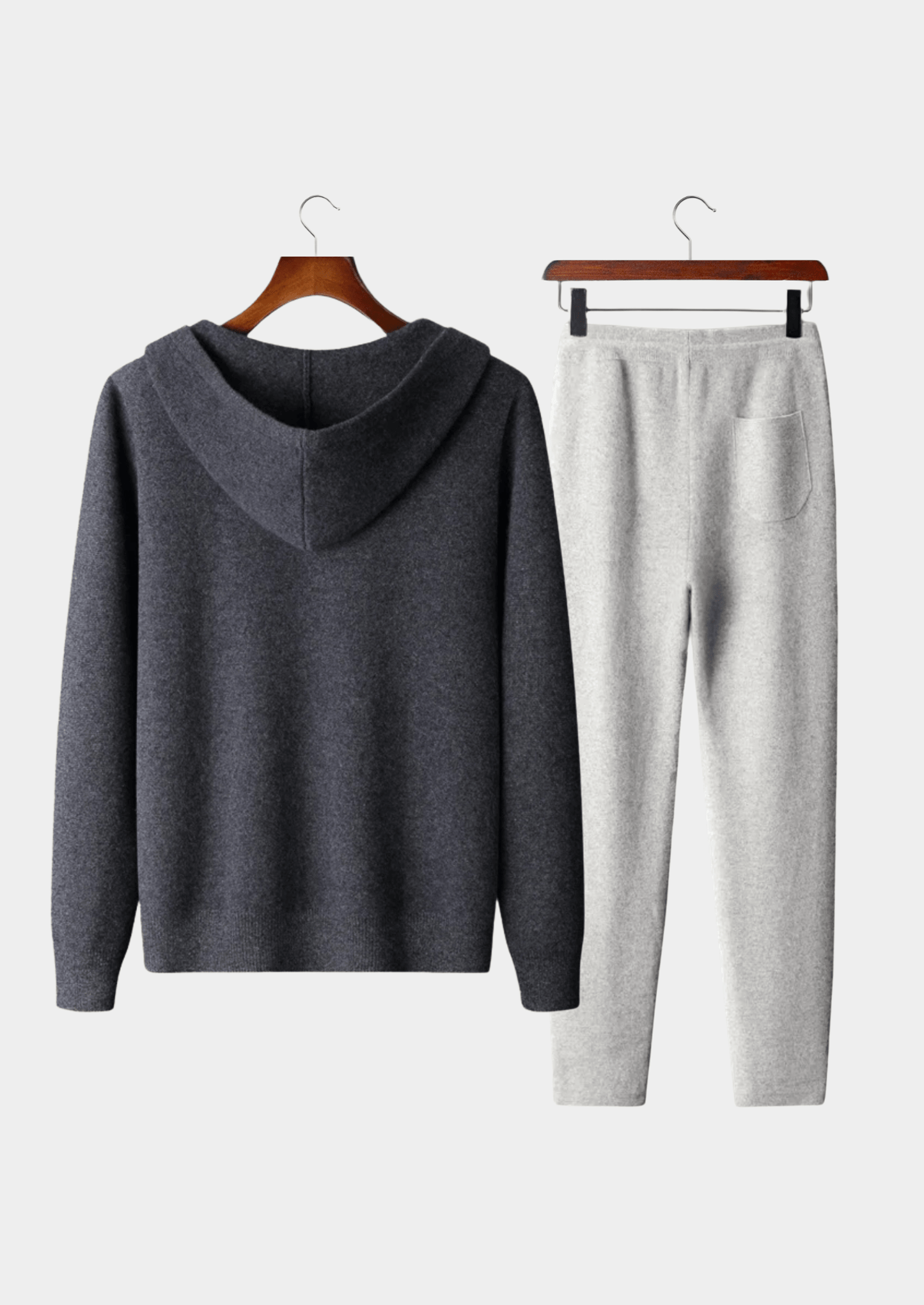 Gray hoodie and pants set on hangers against a white background