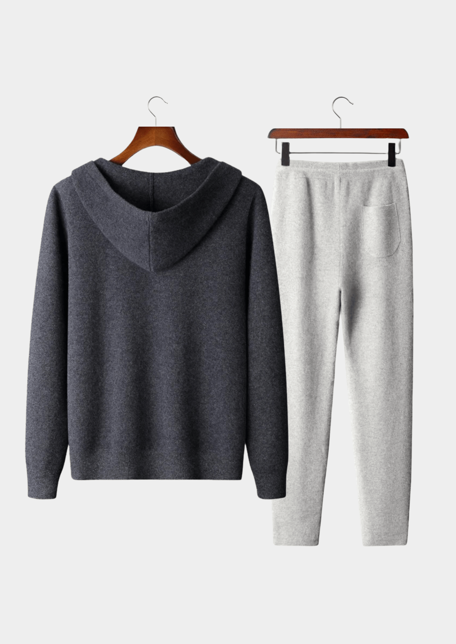 Gray hoodie and pants set on hangers against a white background