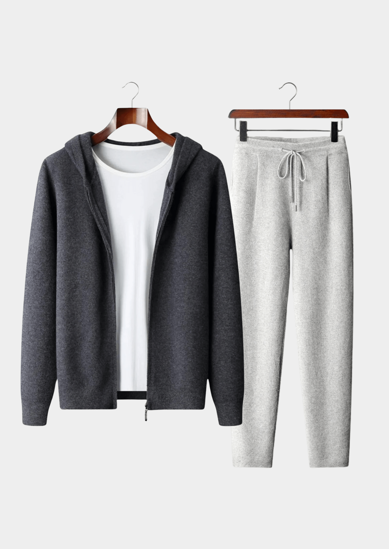 Gray hoodie and pants set on hangers against a white background