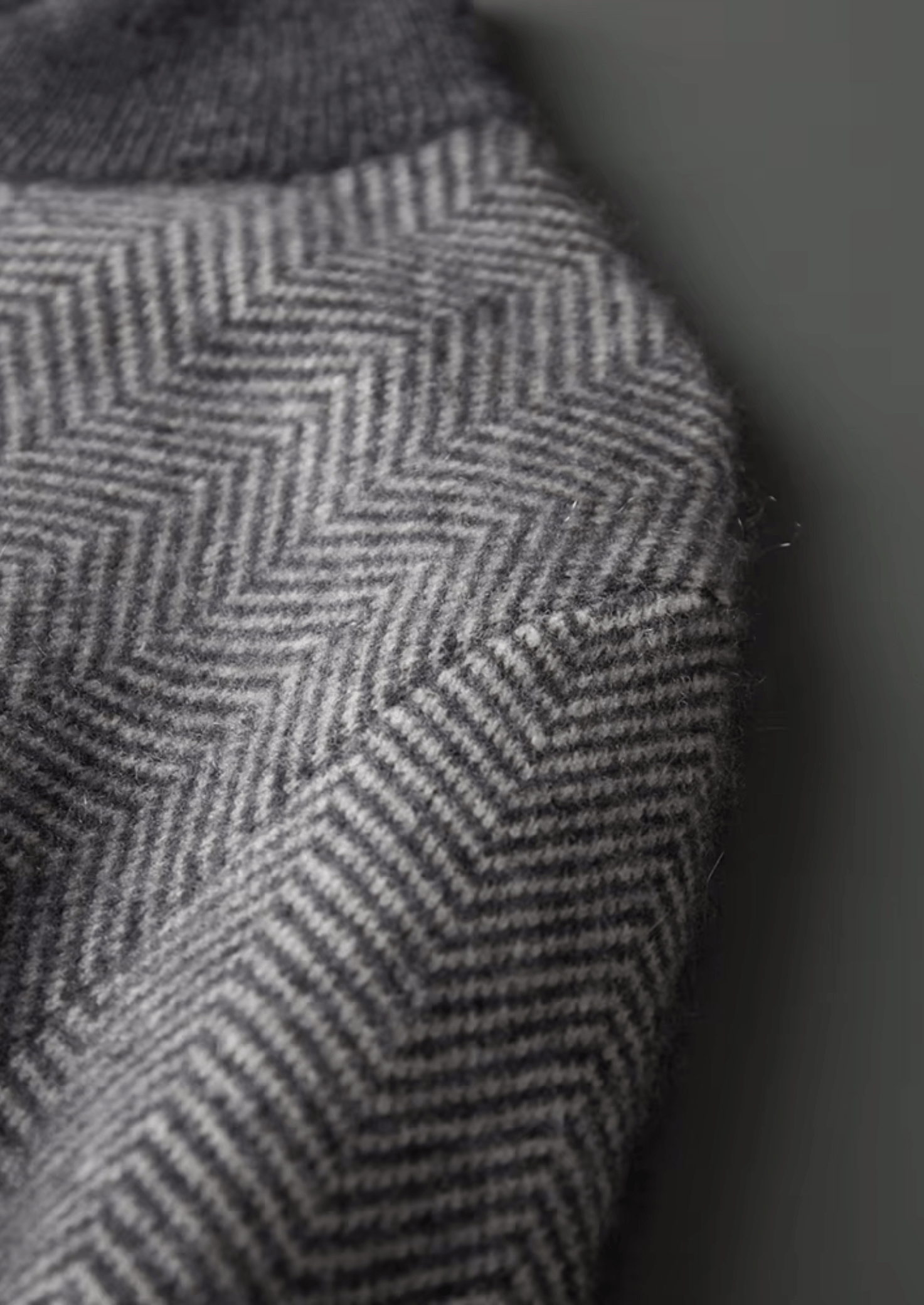 Close-up of a textured fabric with a herringbone pattern on a dark background