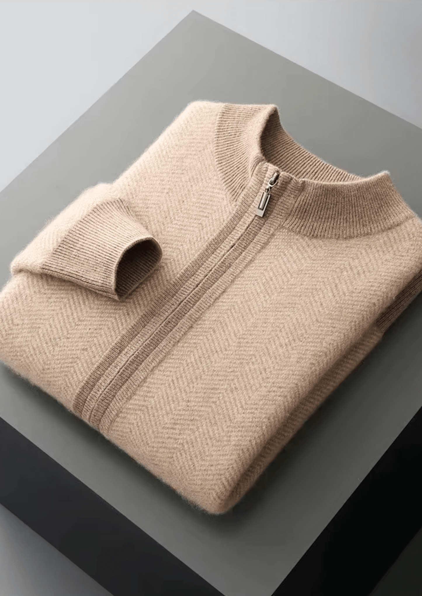 Folded beige sweater with a zipper on a gray surface