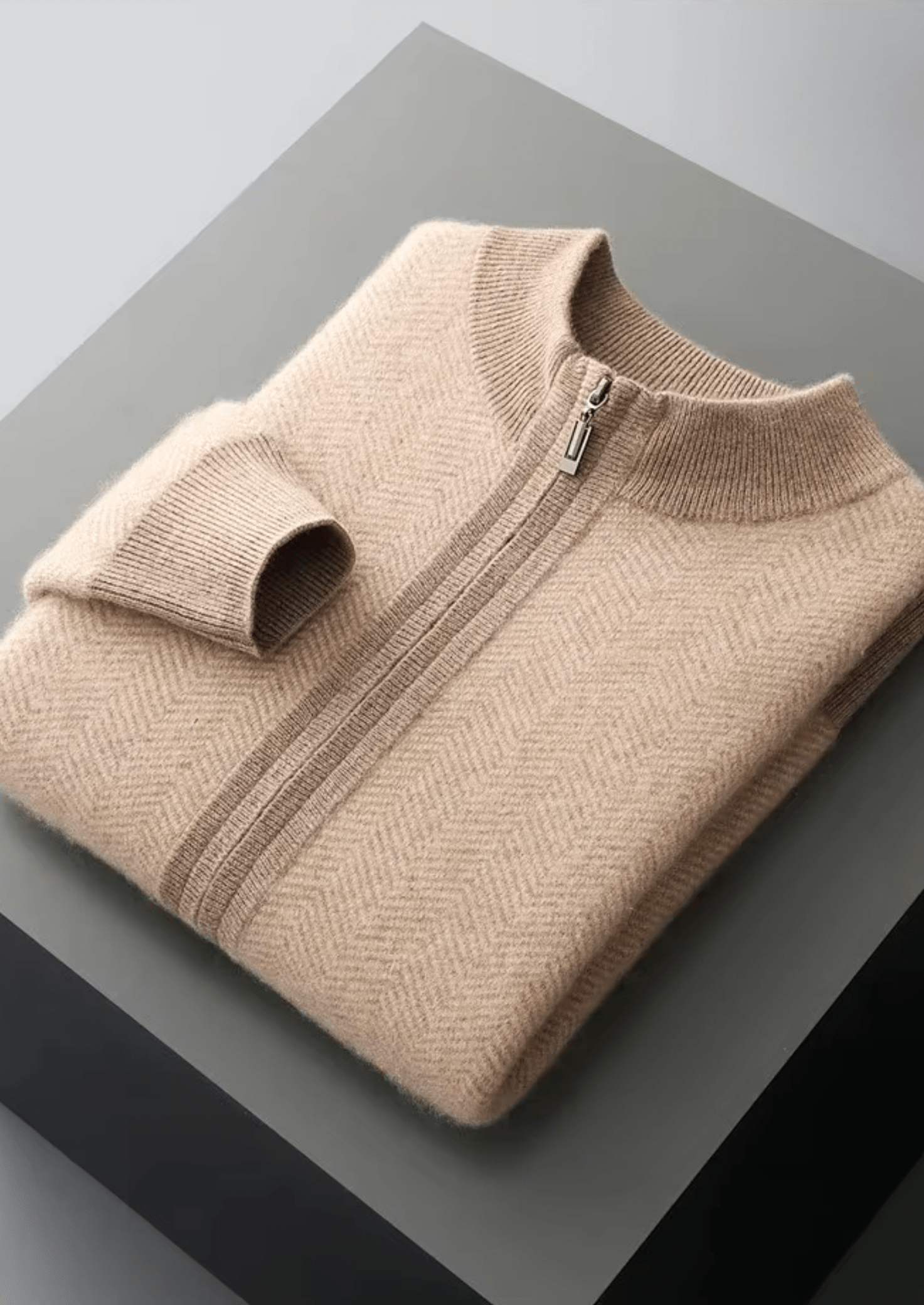 Folded beige sweater with a zipper on a gray surface
