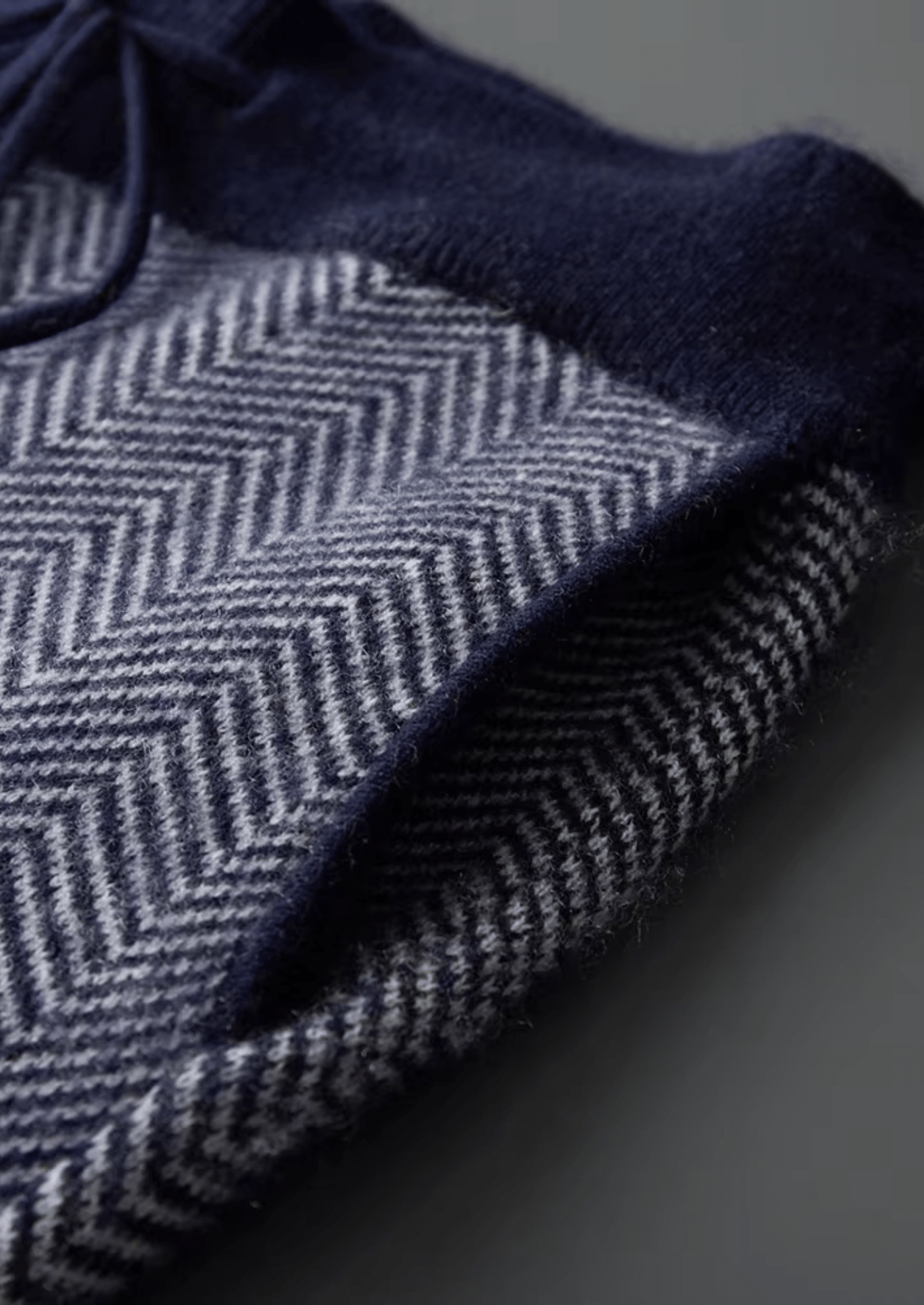 Close-up of a dark blue fabric with a herringbone pattern on a gray background