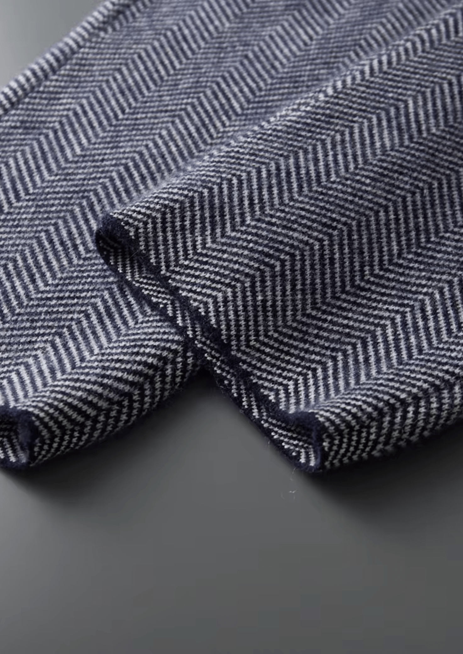 Close-up of a herringbone patterned fabric with blue and white colors on a dark background.