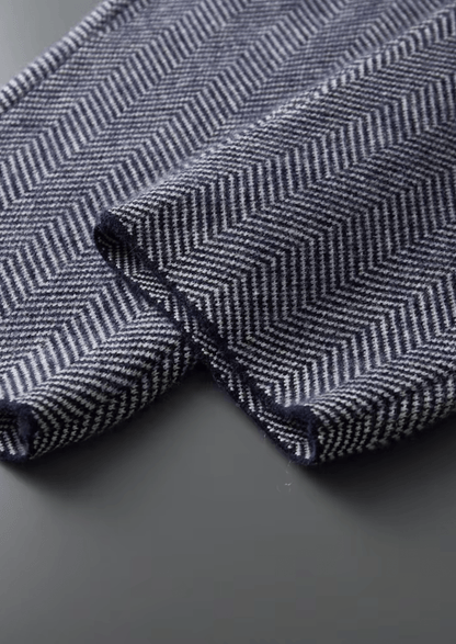 Close-up of a herringbone patterned fabric with blue and white colors on a dark background.