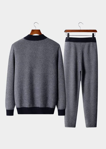 Gray sweater and pants set on hangers against a white background