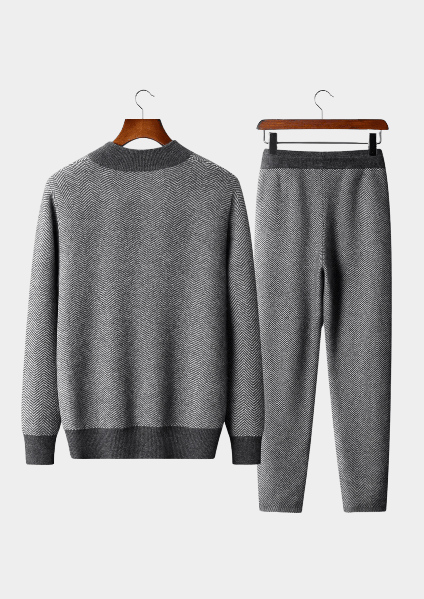 Gray sweater and pants set on hangers against a white background