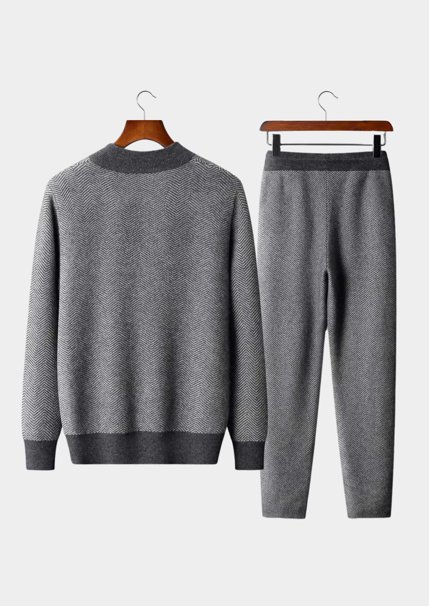 Gray sweater and pants set on hangers against a white background