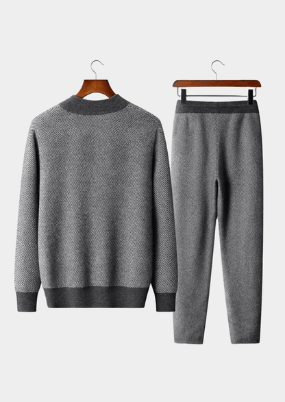 Gray sweater and pants set on hangers against a white background