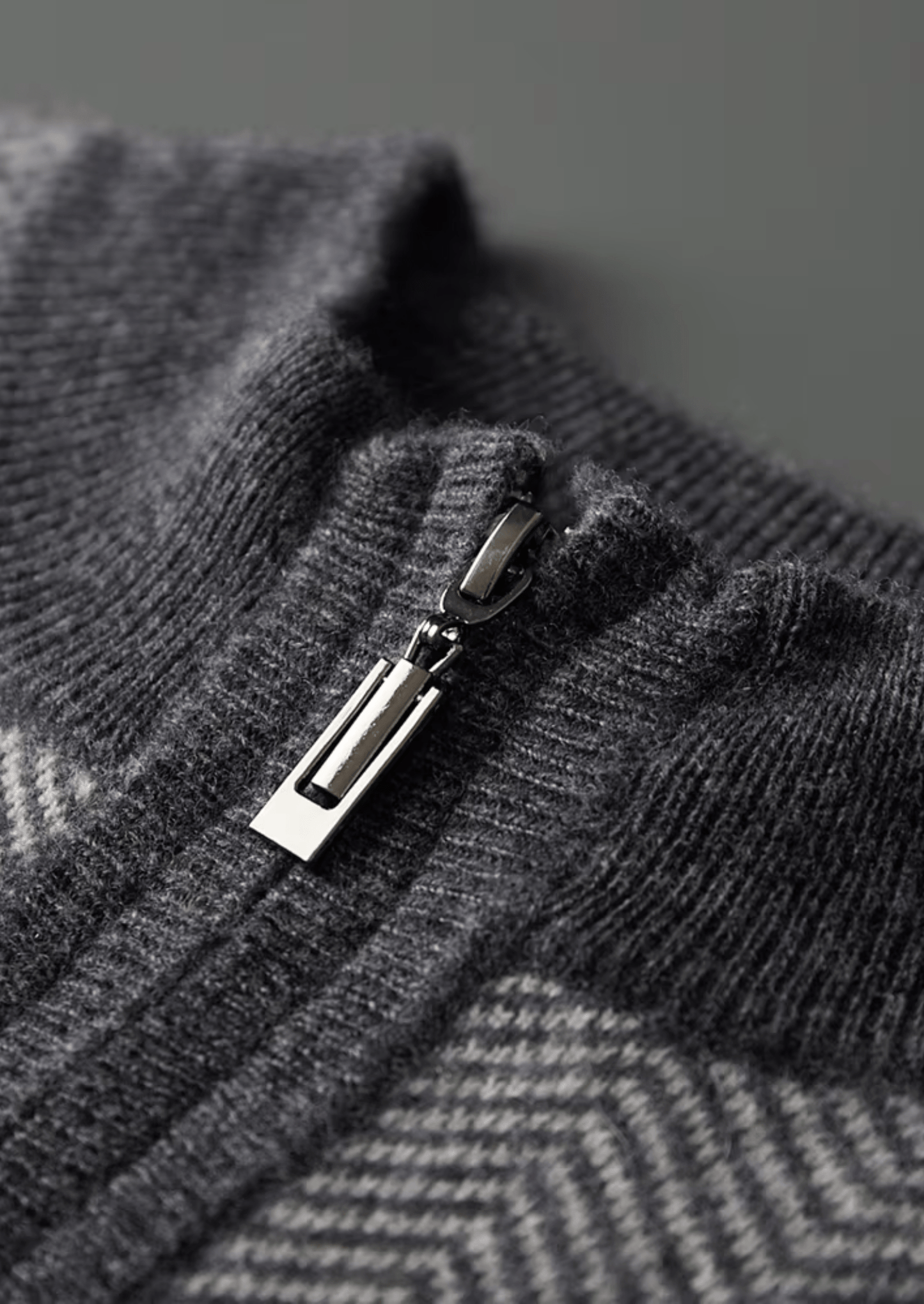 Close-up of a gray textured fabric with a zipper pull.