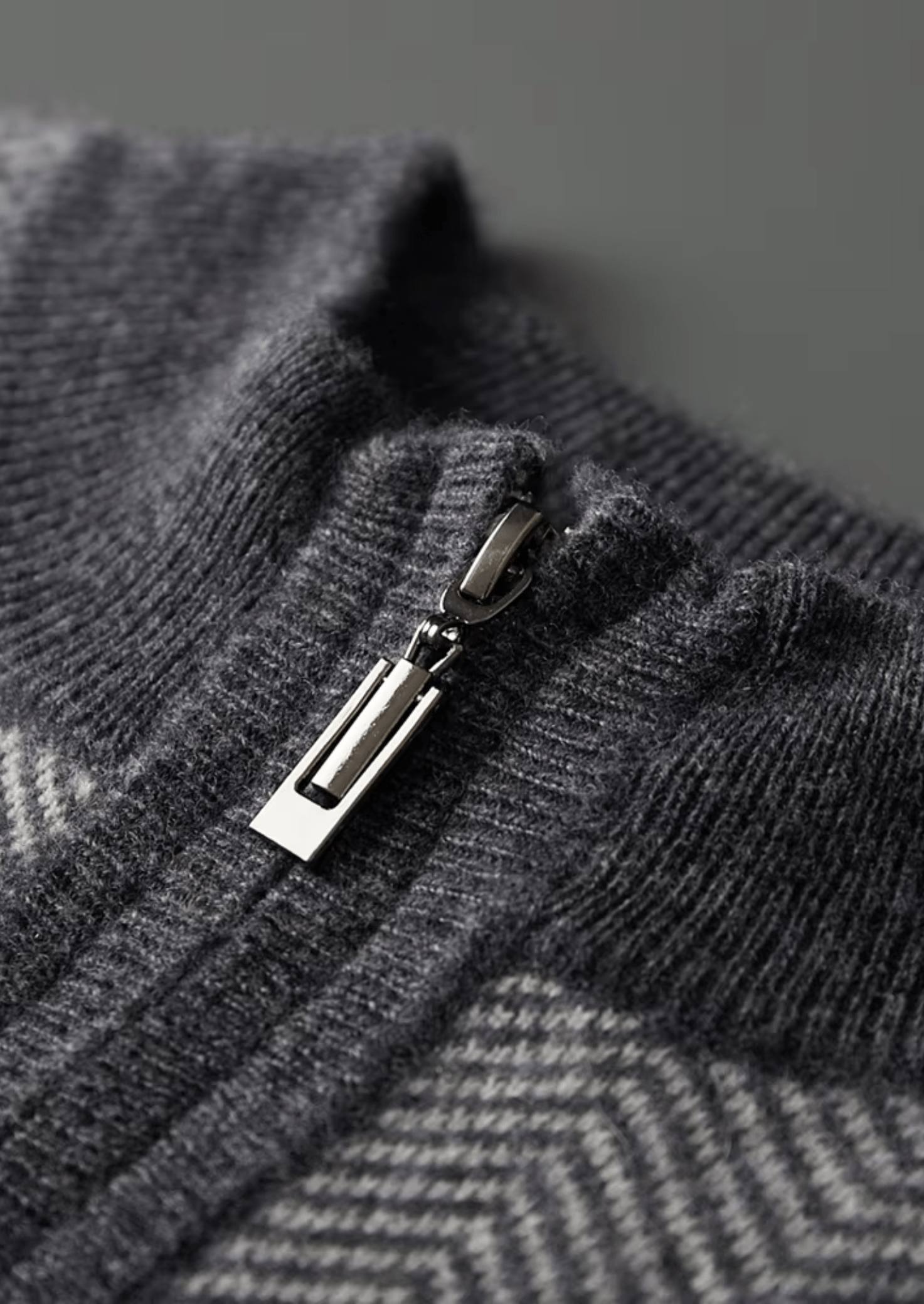 Close-up of a gray textured fabric with a zipper pull.