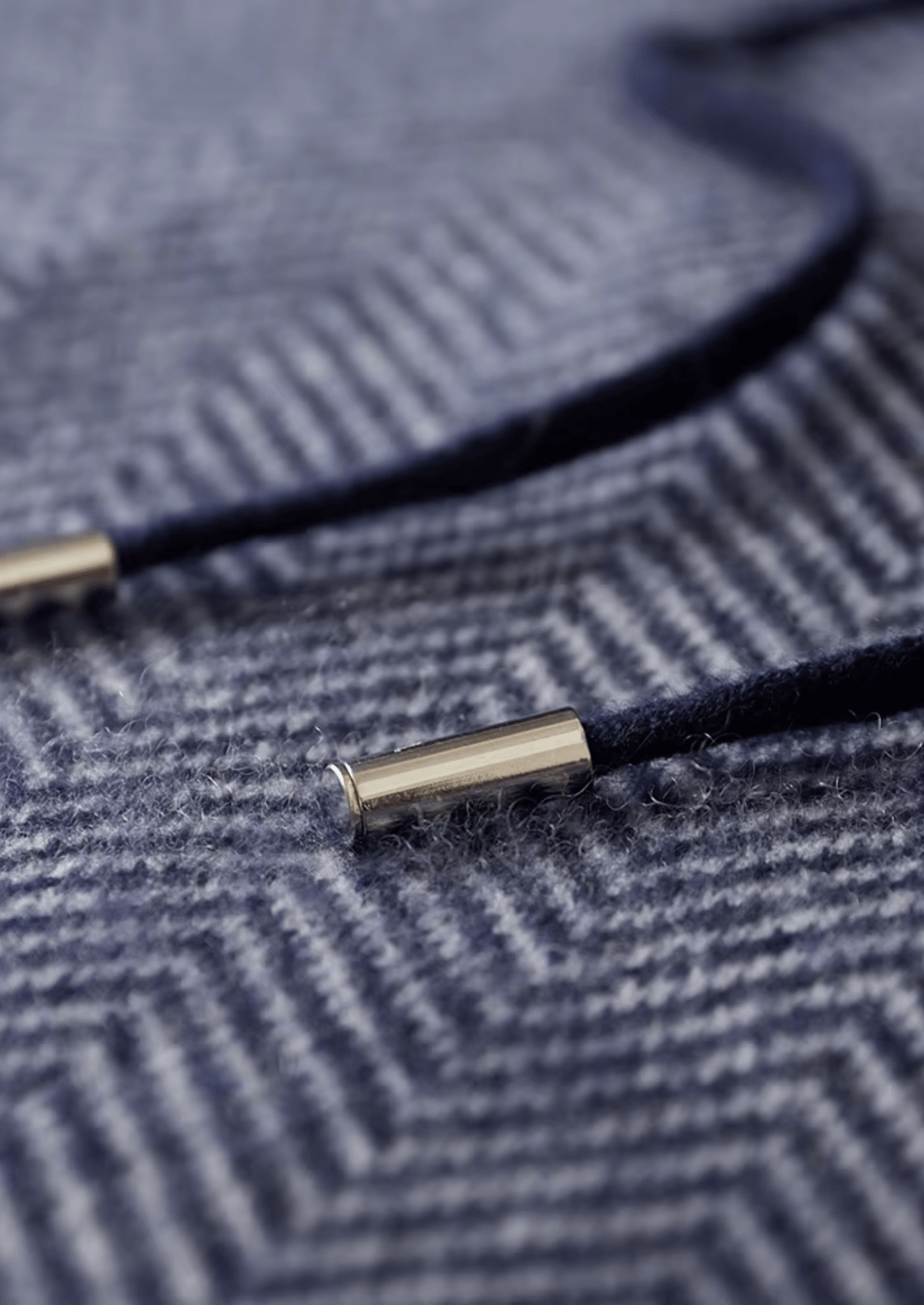 Close-up of a navy blue cord with gold metal end on a textured fabric background