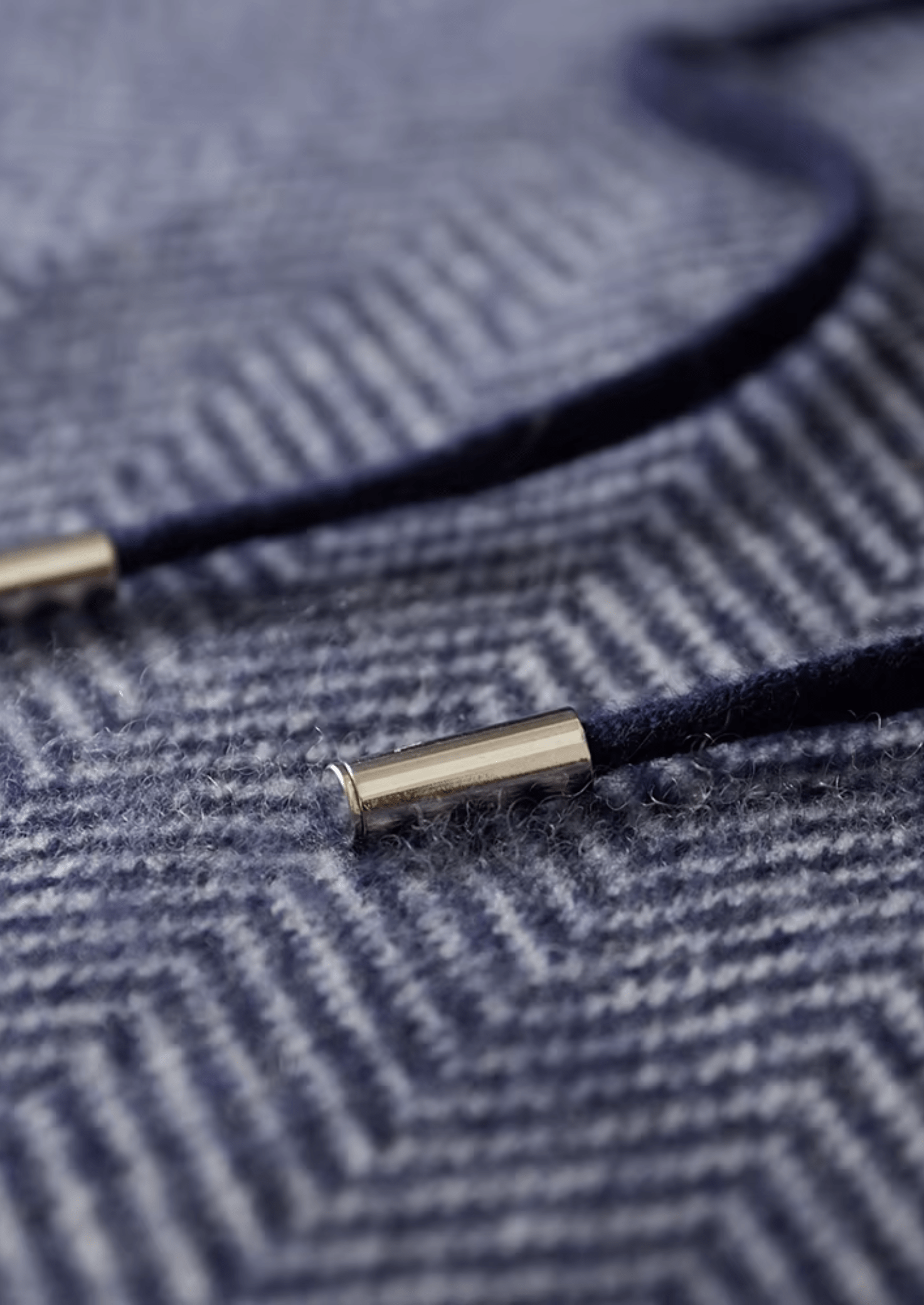 Close-up of a navy blue cord with gold metal end on a textured fabric background
