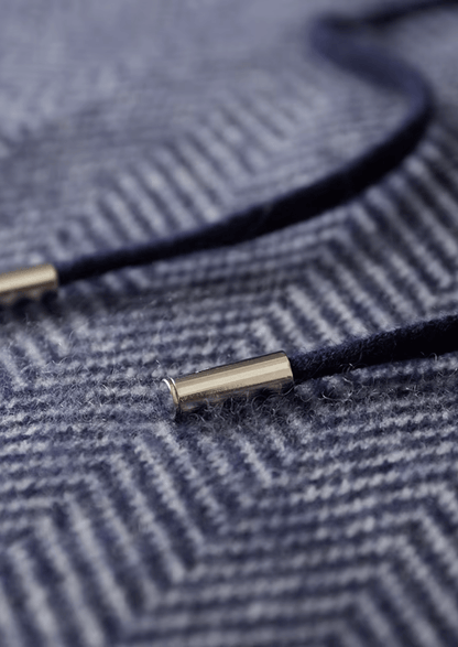 Close-up of a navy blue cord with gold metal end on a textured fabric background