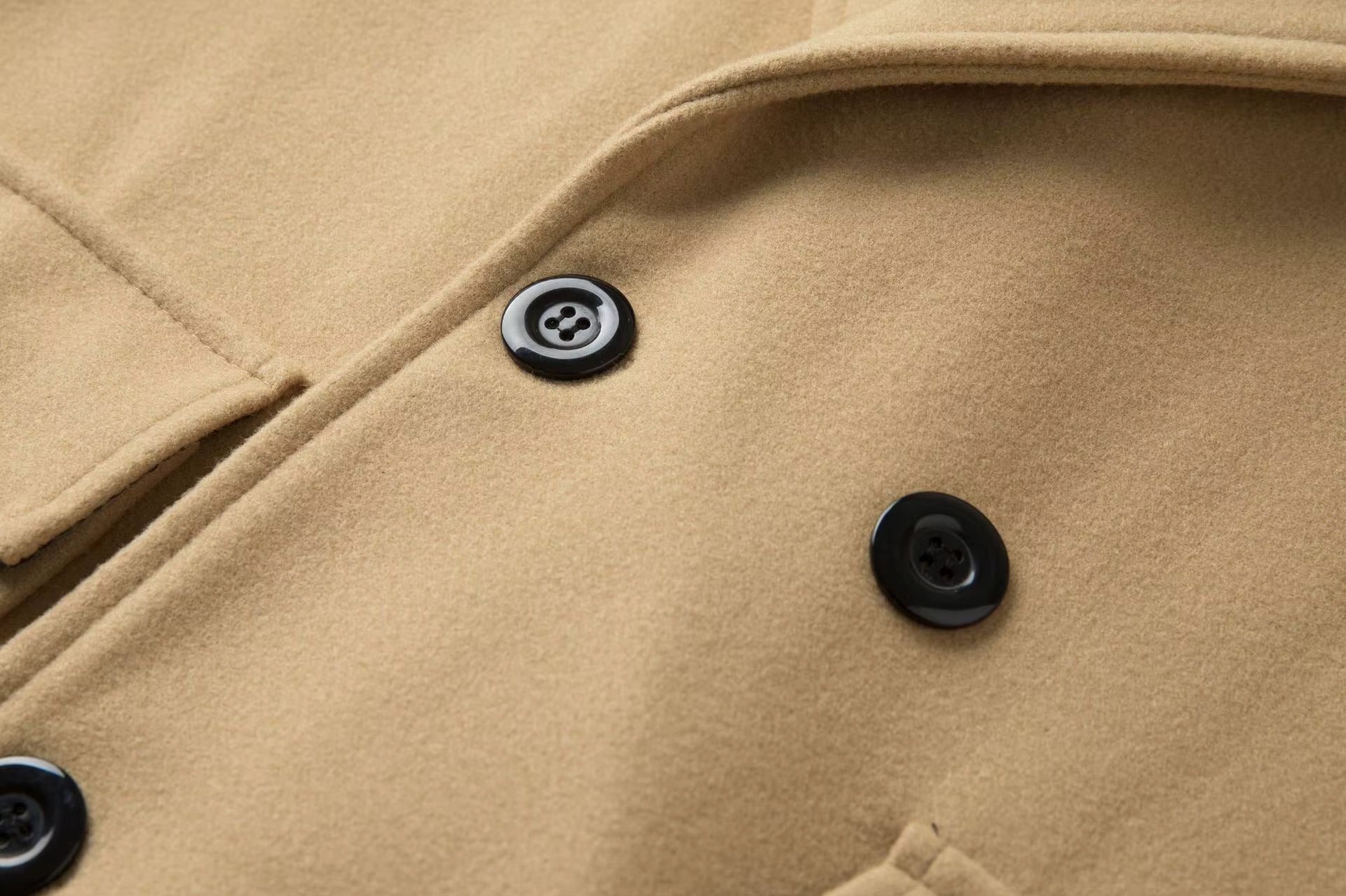 Close-up of a beige coat with black buttons