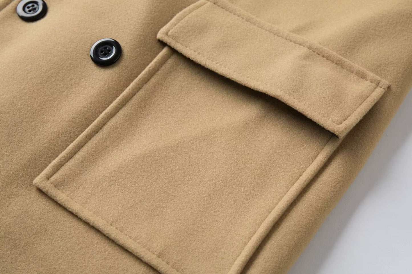 Close-up of a beige coat with a pocket and button details on a white background
