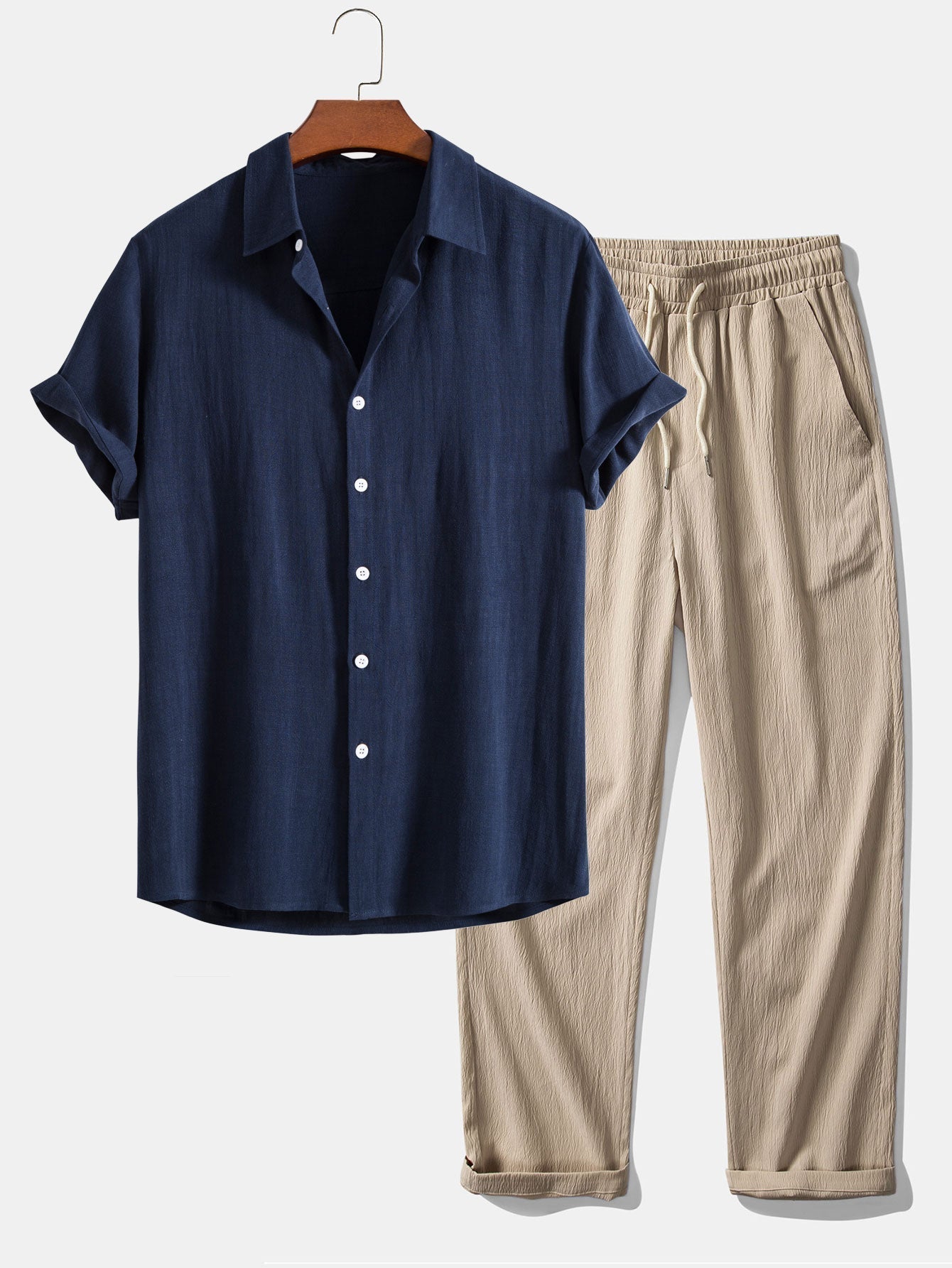 Navy shirt and beige pants on a hanger against a white background