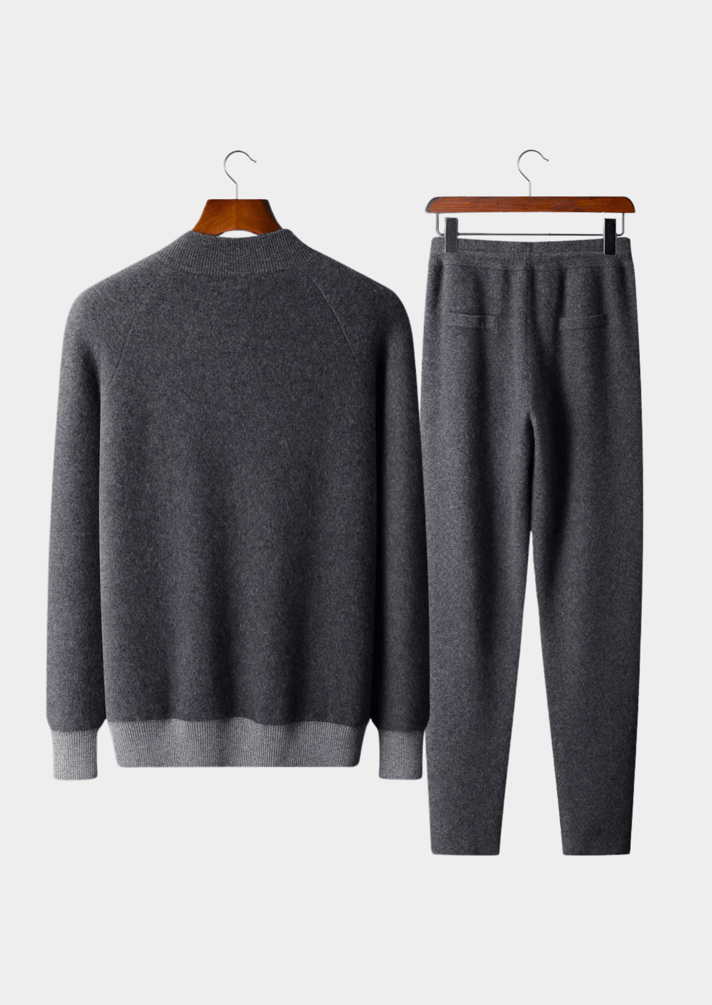 Gray sweater and pants set on hangers against a white background