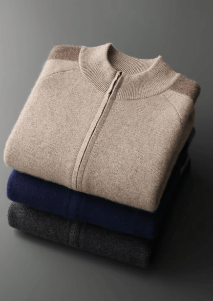 Stack of folded sweaters in beige, blue, and gray on a dark background