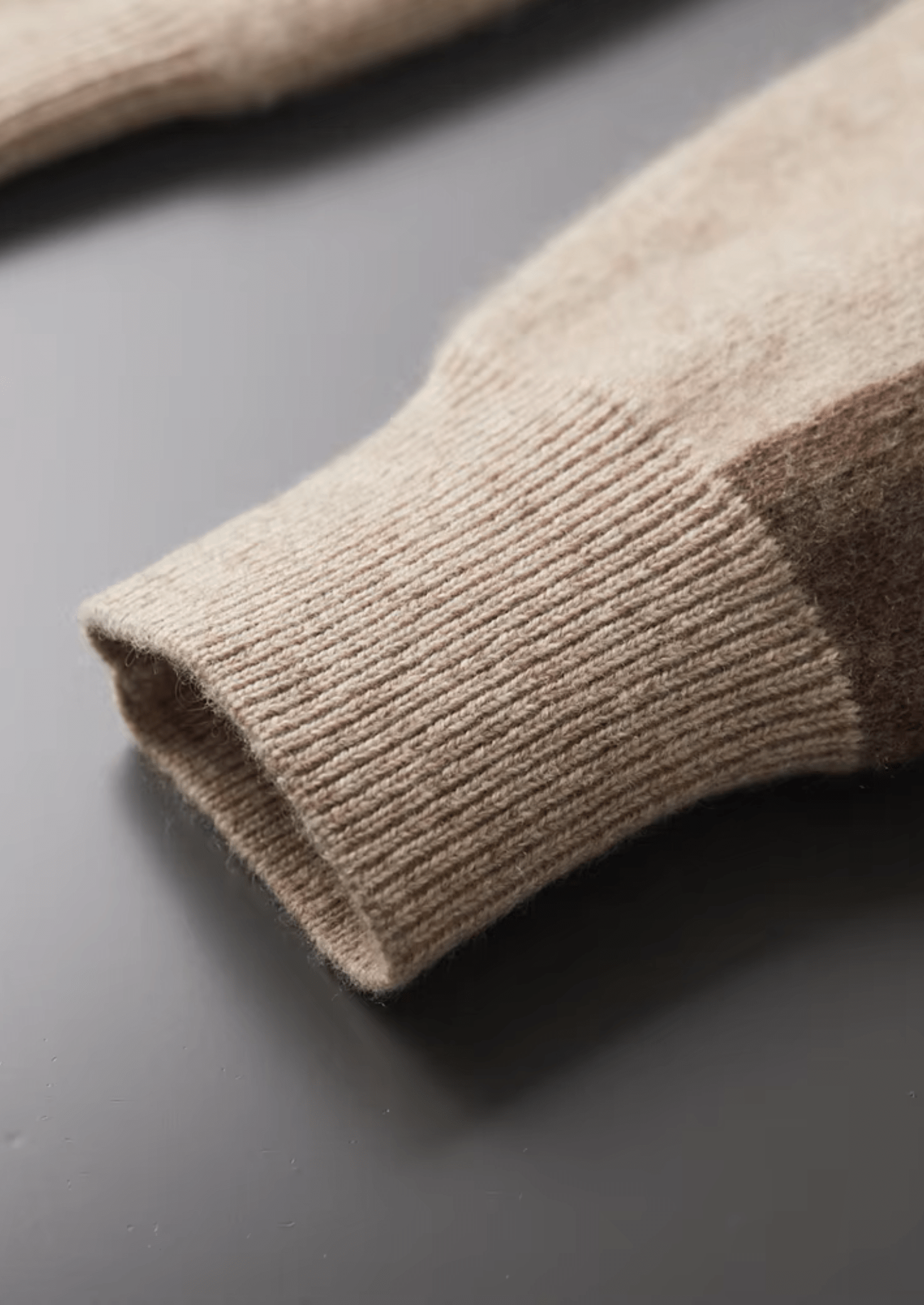 Close-up of a beige sweater sleeve on a gray surface