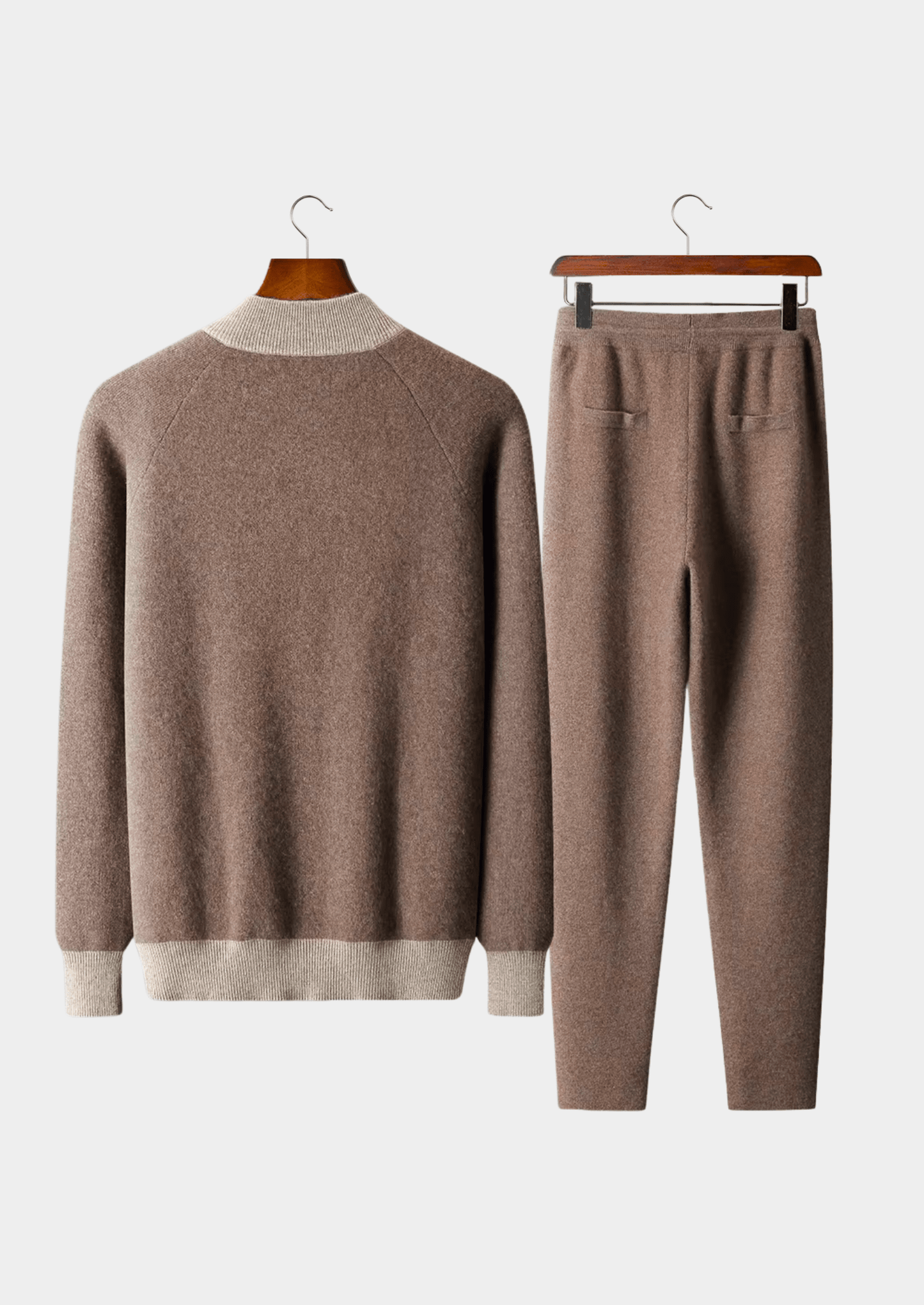 Brown sweater and pants set on hangers against a white background