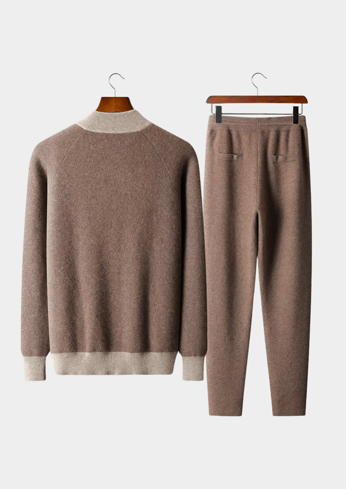 Brown sweater and pants set on hangers against a white background