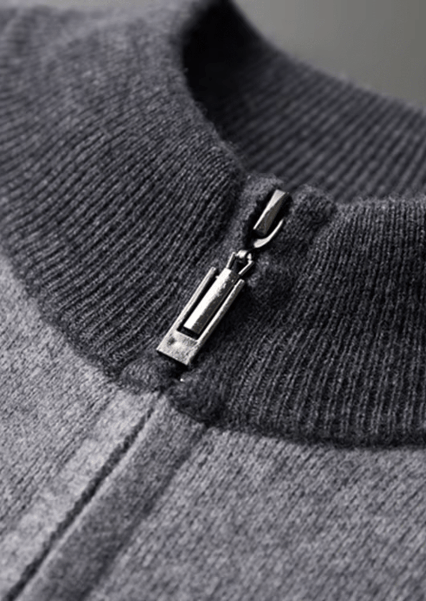 Close-up of a gray sweater with a zipper detail on a gray background