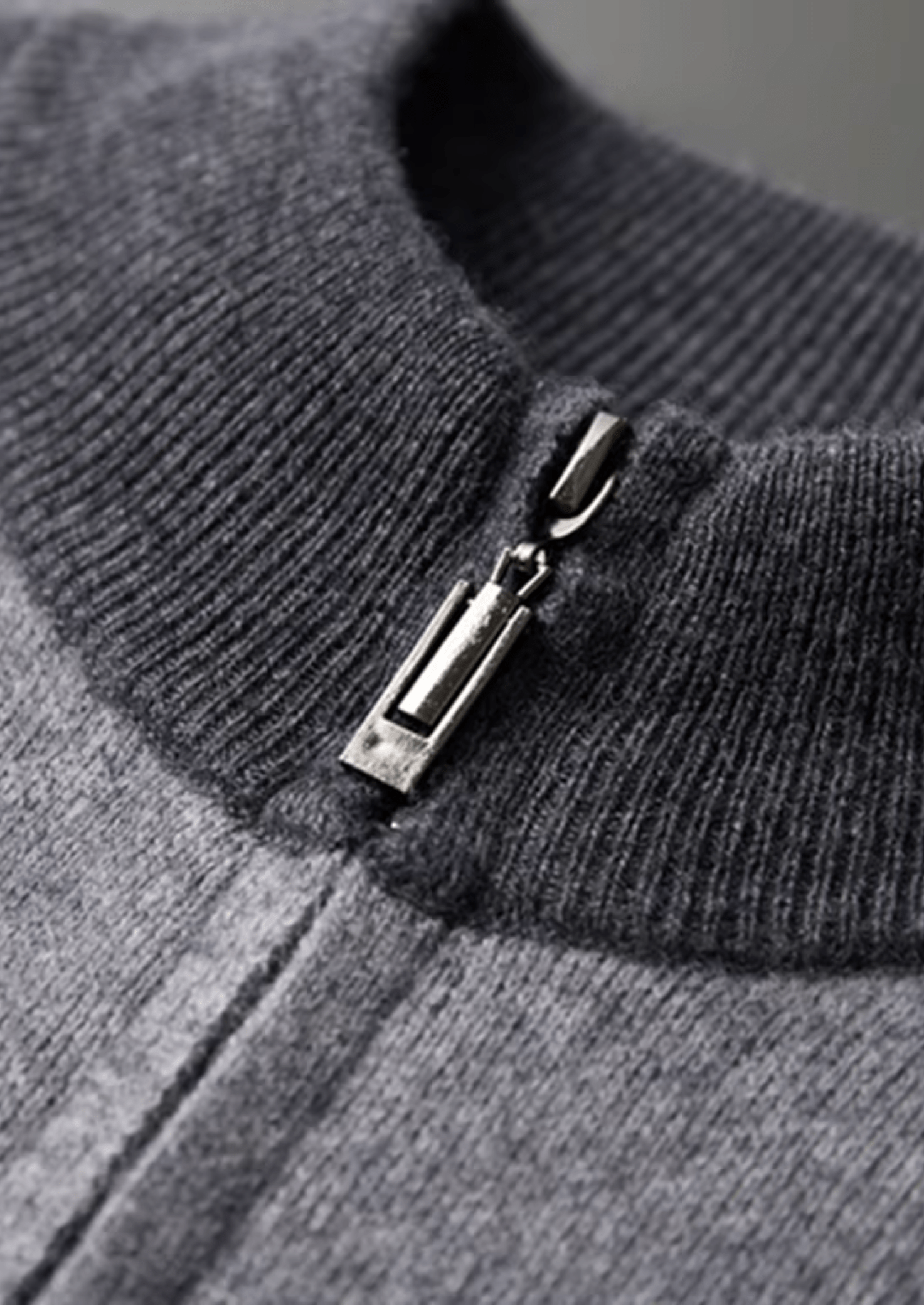 Close-up of a gray sweater with a zipper detail on a gray background