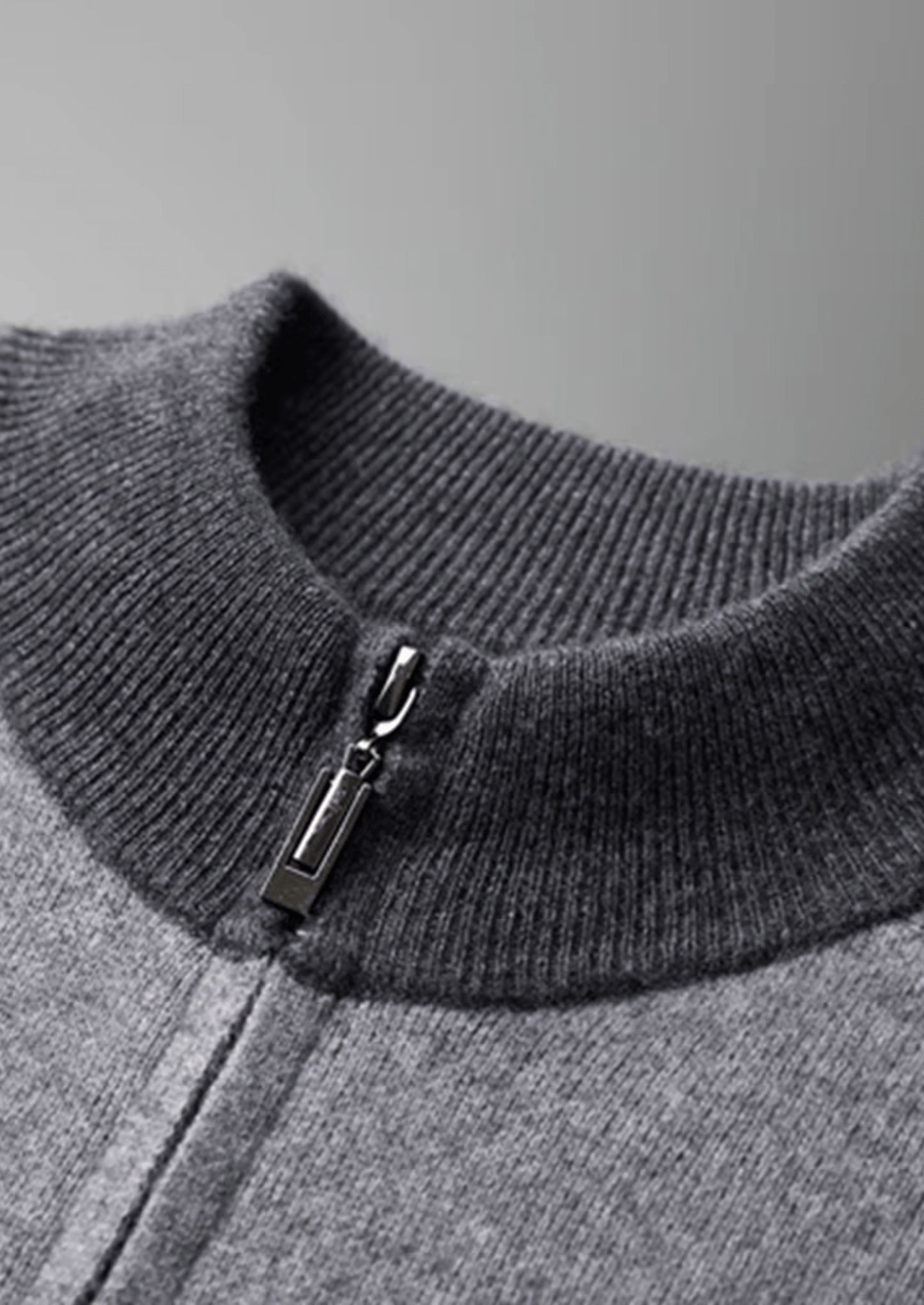 Close-up of a gray sweater with a zipper detail on a gray background
