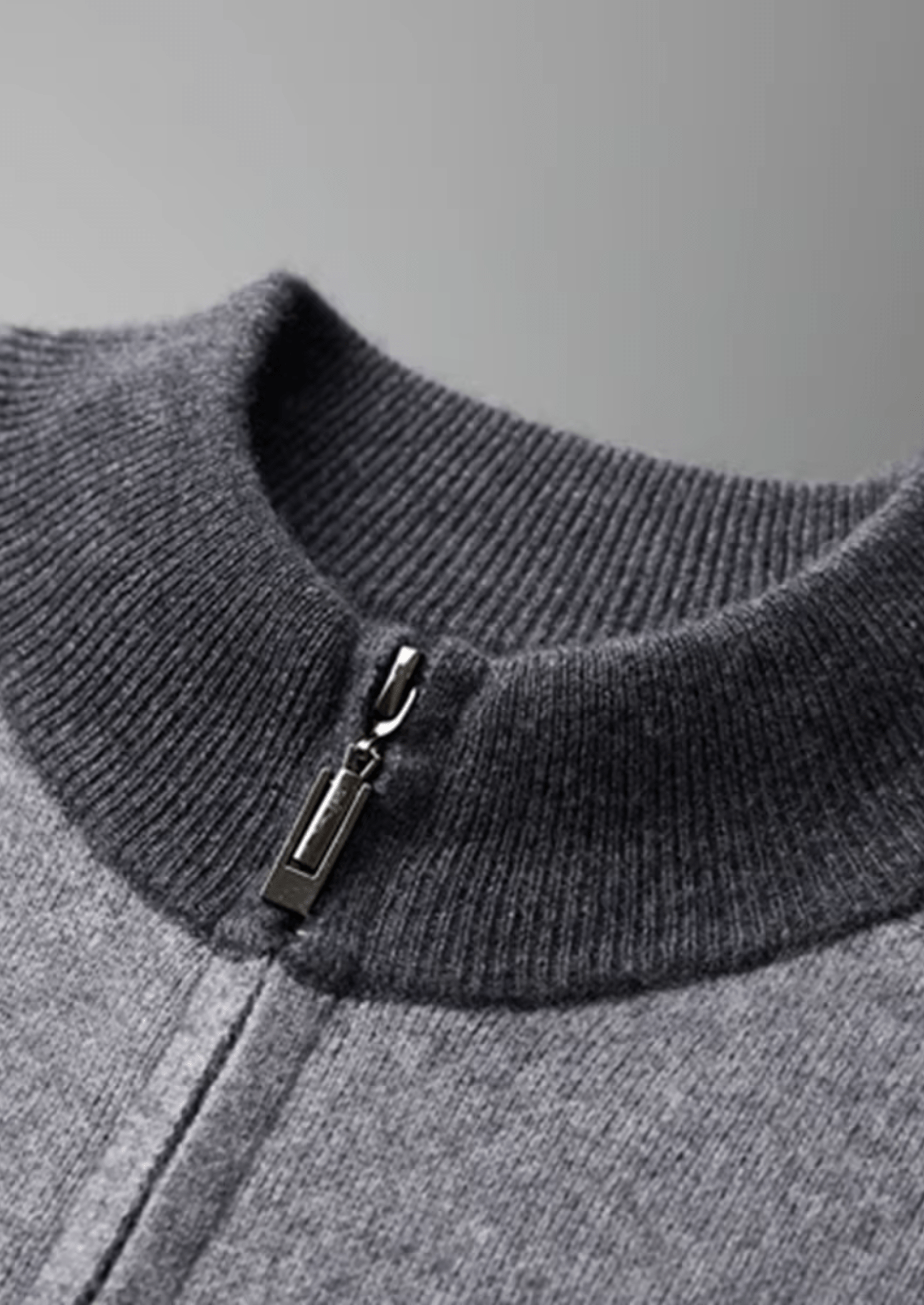 Close-up of a gray sweater with a zipper detail on a gray background