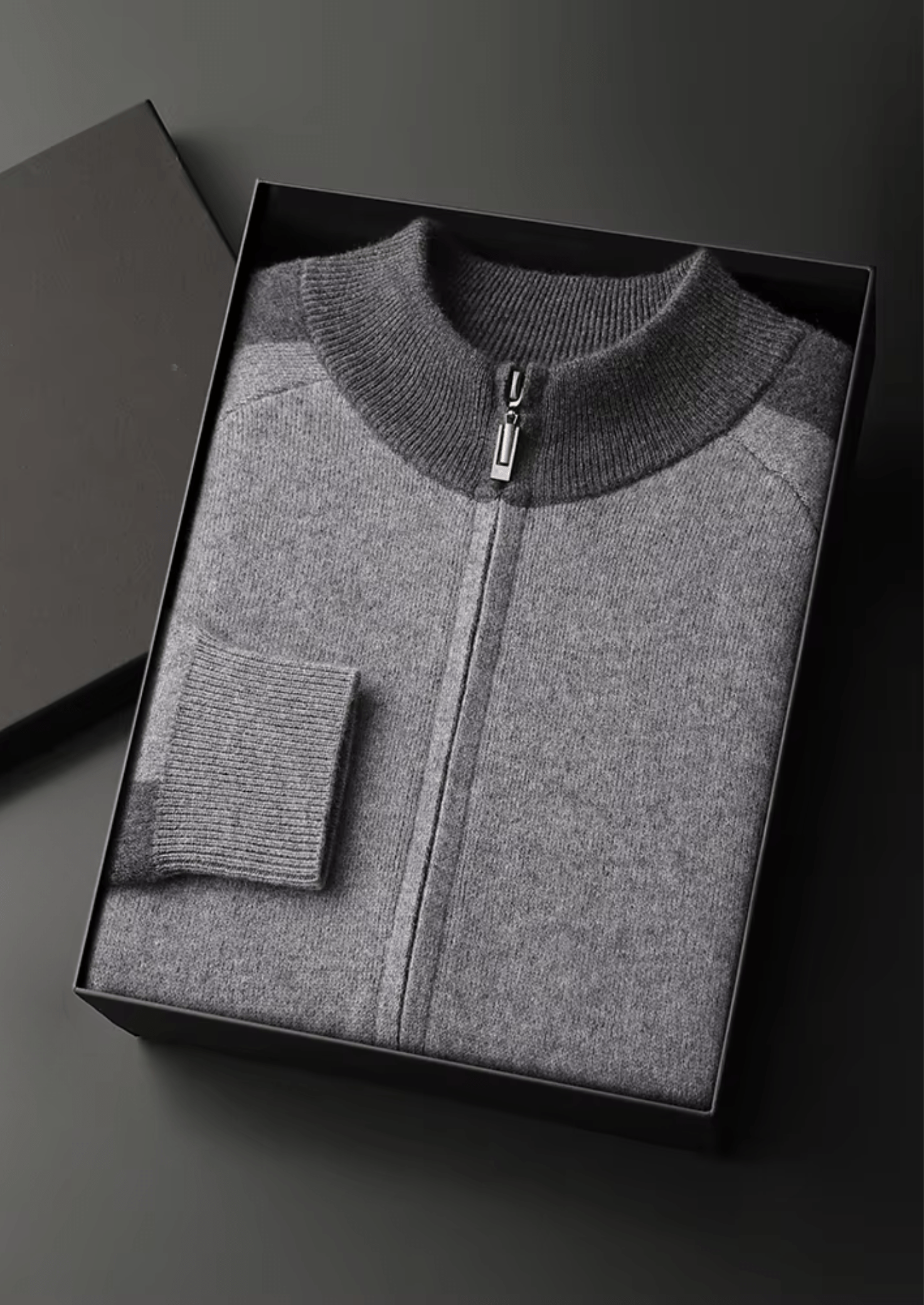 Gray zip-up sweater in a black box on a dark background