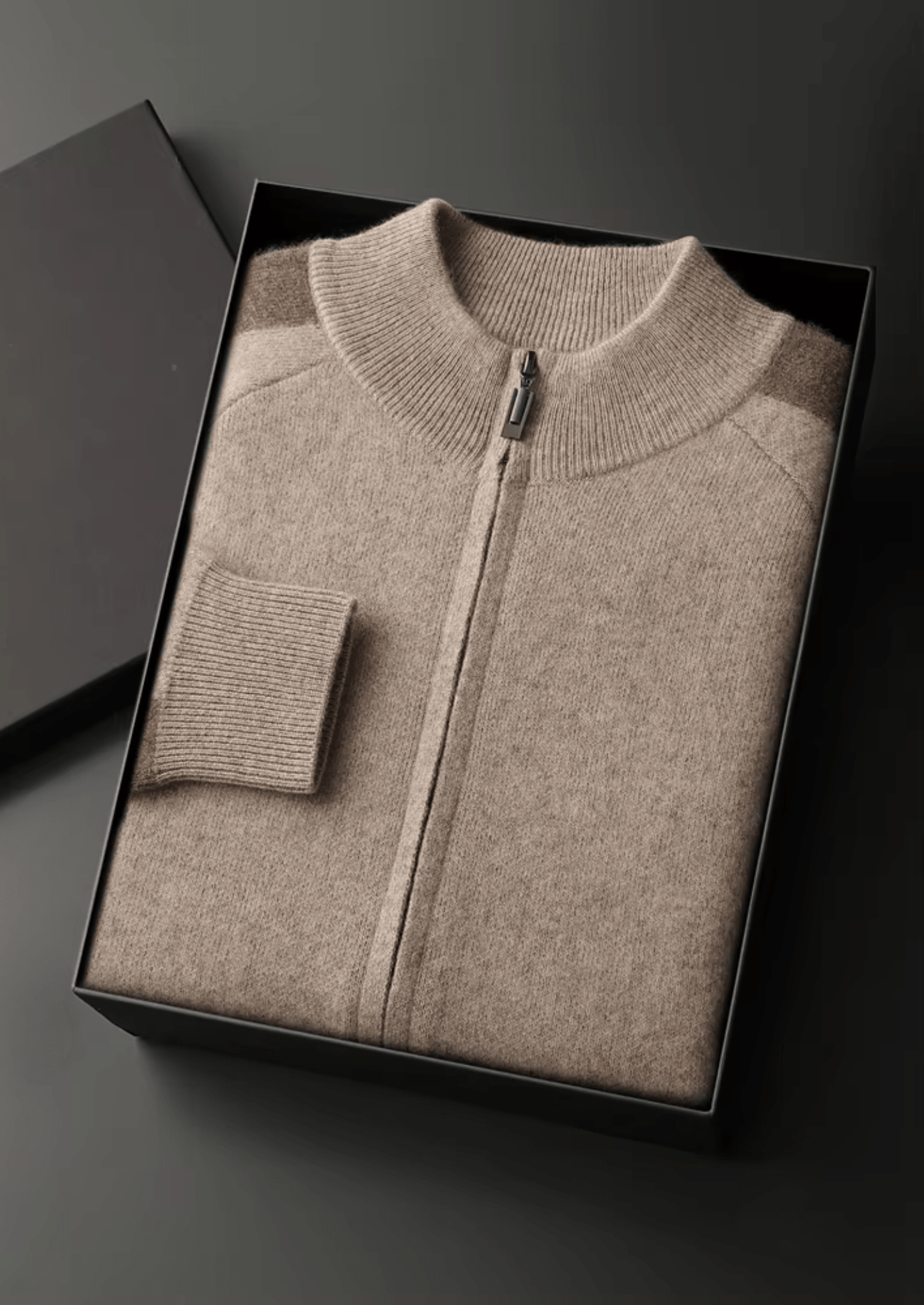 Beige zip-up sweater in a black box on a dark background
