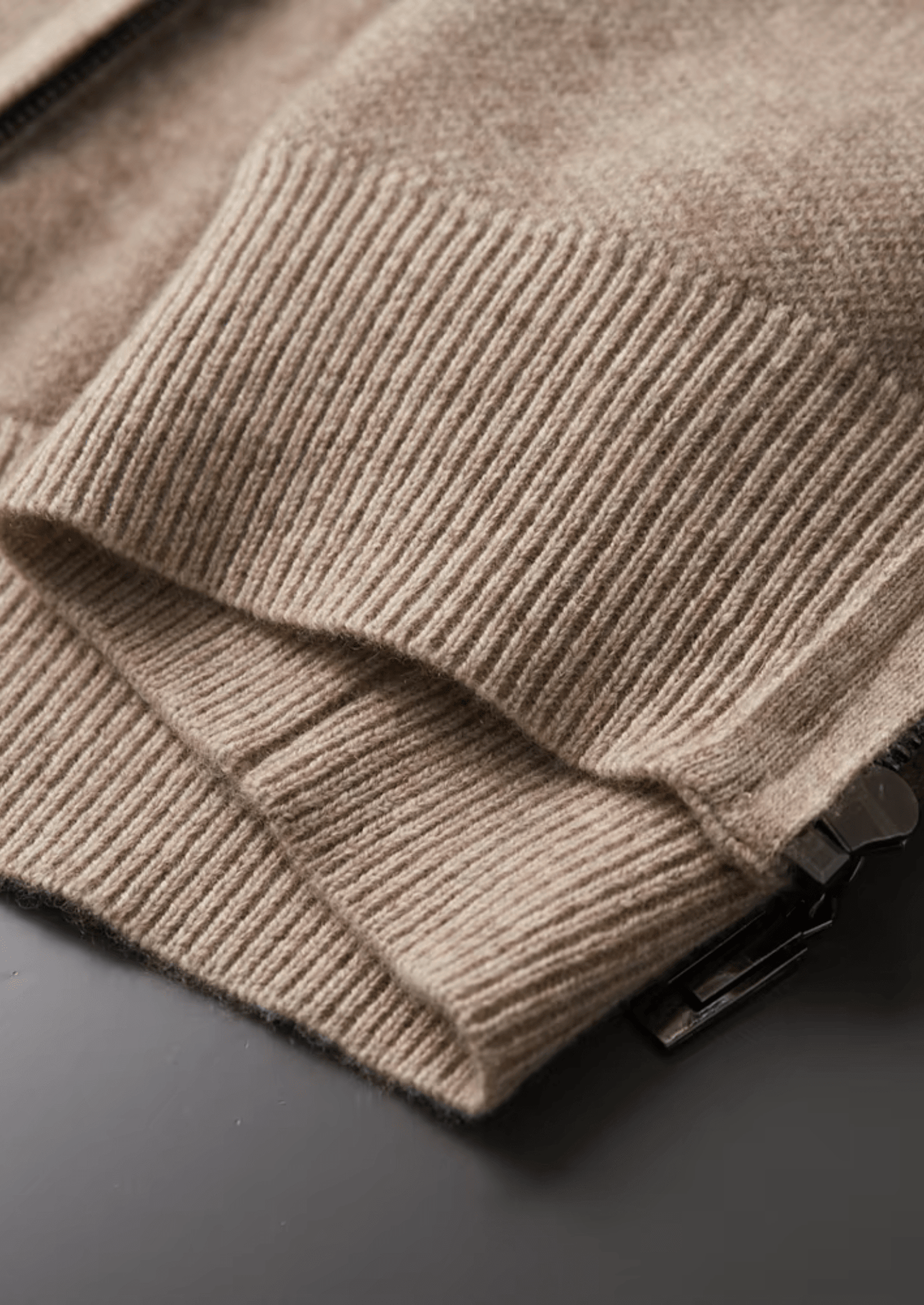 Close-up of a beige knitted sweater on a dark surface
