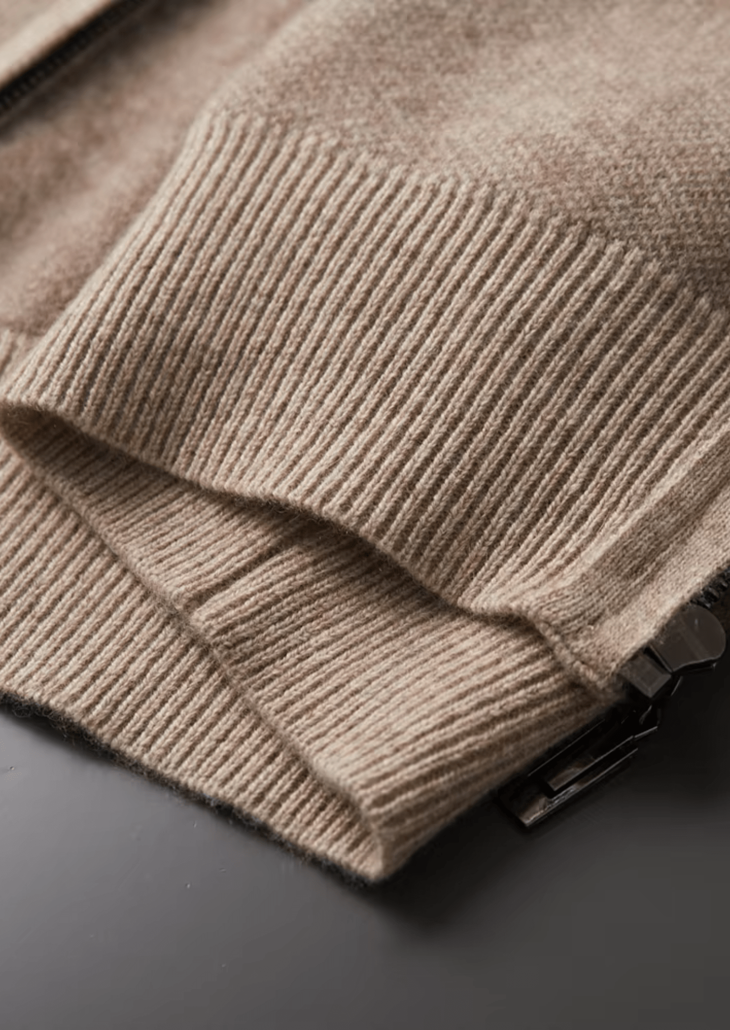 Close-up of a beige knitted sweater on a dark surface