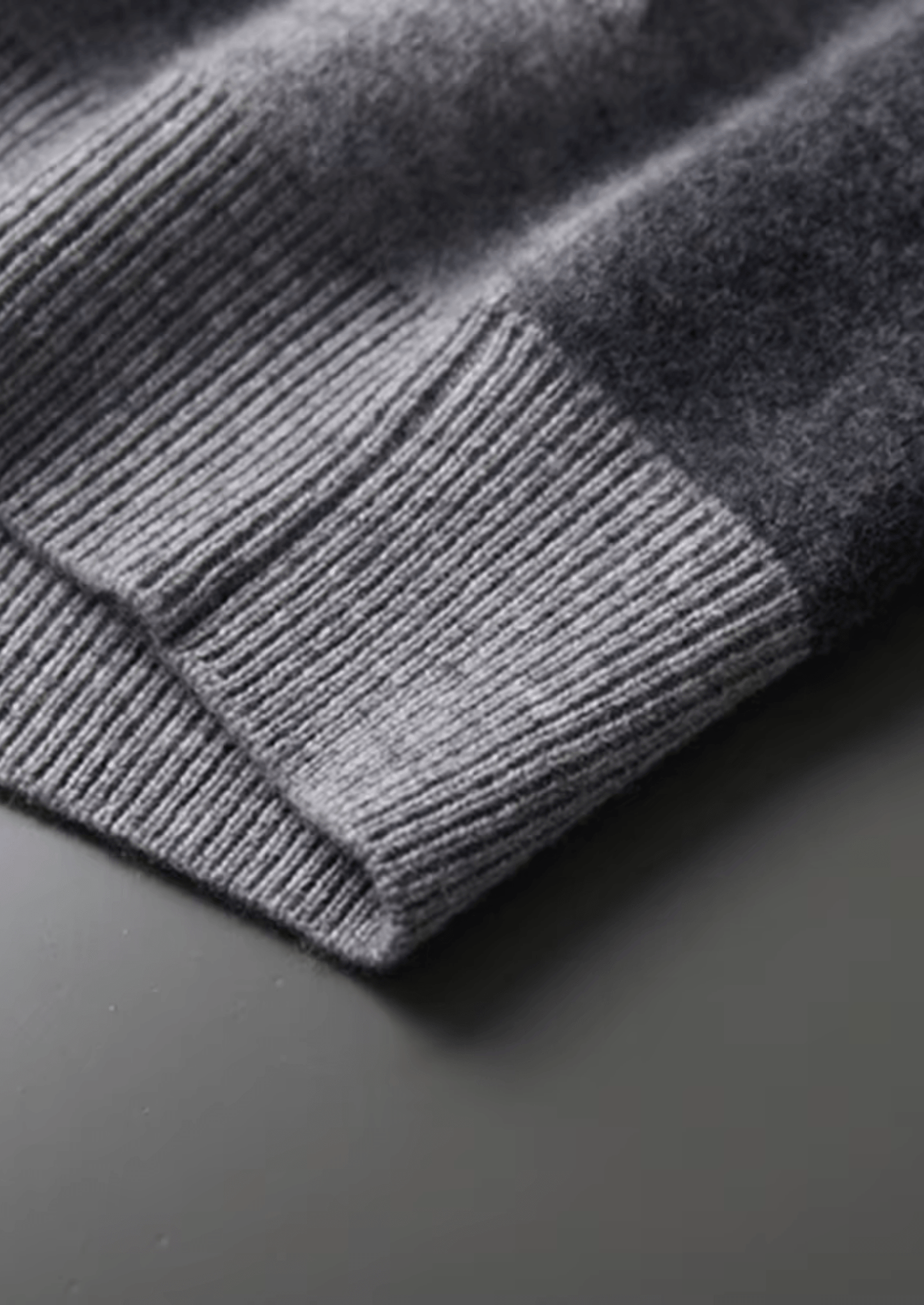Close-up of a gray knitted sweater on a dark surface