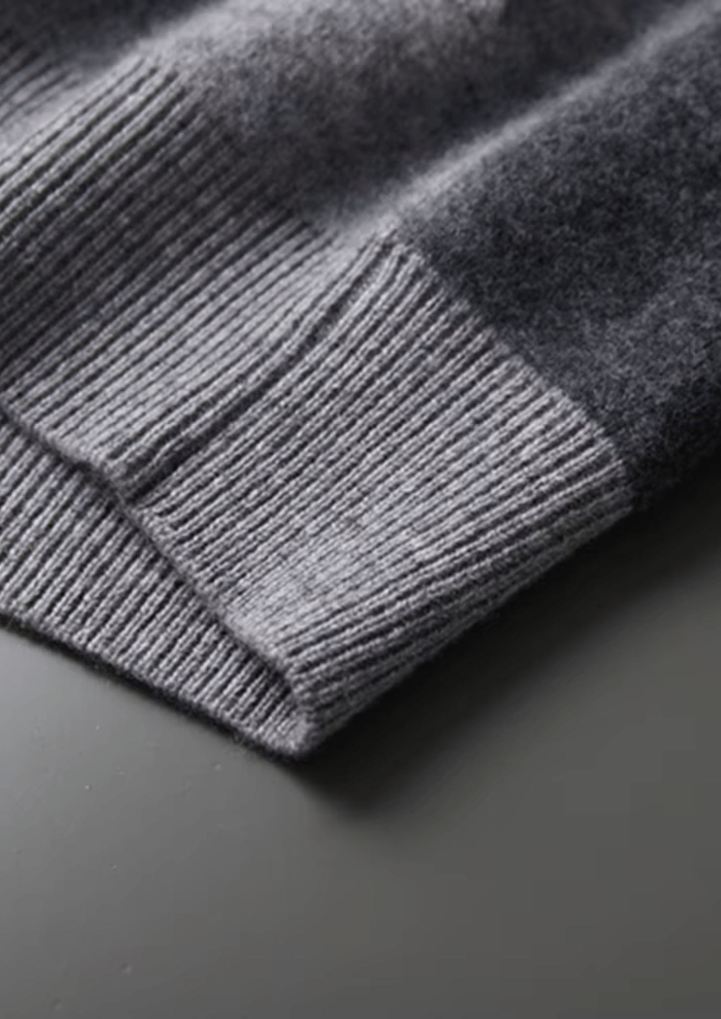 Close-up of a gray knitted sweater on a dark surface