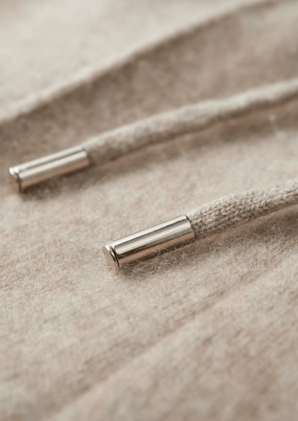 Close-up of a textured cord with metallic ends on a beige fabric background