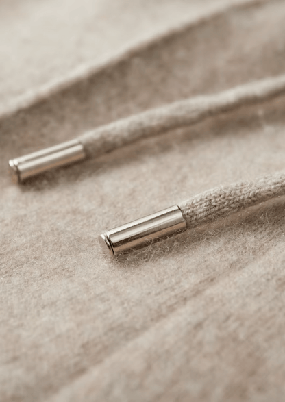 Close-up of a textured cord with metallic ends on a beige fabric background